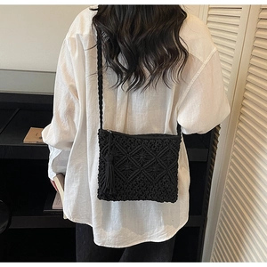 Detail of black macrame woven crossbody bag with geometric patterns and fringe tassels