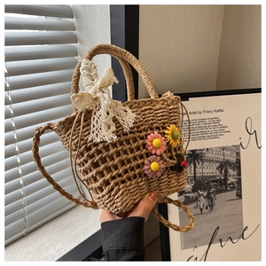 Detail of hand-woven straw bucket bag with lace bow and colorful crochet flowers