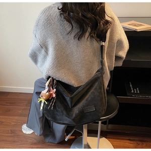 Détail du grand sac hobo noir avec étiquette fashion et pendentif ours mignon