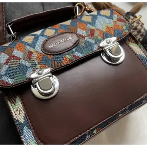 Gros plan sur le tissu tissé géométrique et les boucles en métal argenté du sac marron