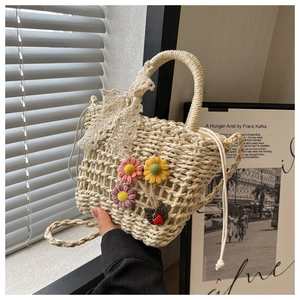Detail of woven straw bag featuring crochet flowers and delicate lace bow decoration