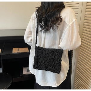 Detail of handmade woven crossbody bag with black geometric patterns and long side tassels