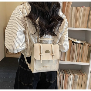 Detailopname van beige vintage rugzak met gespen gedragen door model in een bibliotheek