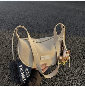 Detail of cream dumpling shoulder bag with adjustable straps and cute bear charm pendant