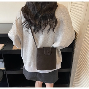 Sac seau minimaliste en cuir mat porté par un mannequin pour référence de style et taille