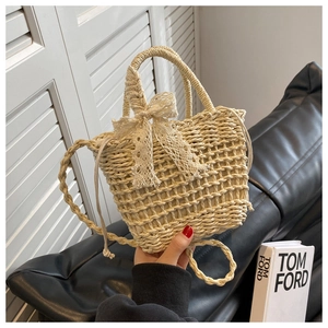 Detailed texture of beige woven straw bag with lace bow and drawstring closure