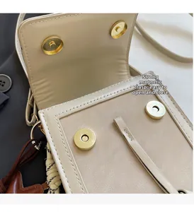 Detail view of the beige crossbody bag featuring double magnetic snap button closure