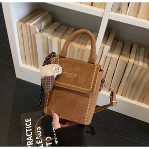 Detail of vintage brown textured leather handbag with gold studs and pinecone charm