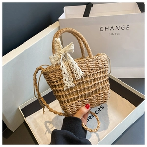 Detail of woven straw handbag featuring hollow mesh texture and a cream lace bow accent