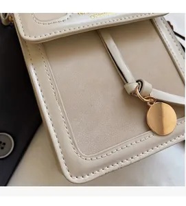 Detail of off-white leather phone bag showing golden logo and stitching