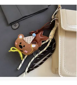 Detail of cute bear plush and star charm attached to a cream shoulder bag strap