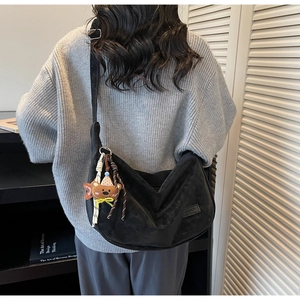 Détail du sac hobo en daim noir avec large bandoulière et pendentif ours mignon
