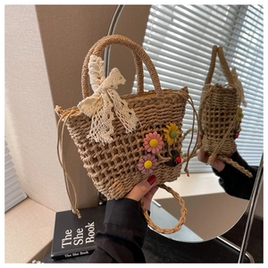 Detail of straw woven bucket bag with 3D floral accents and white lace bow decoration