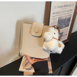 Détail d'un sac seau beige avec fermoir magnétique et pendentif cheval en peluche doux