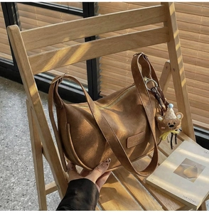 Close-up of vintage brown dumpling bag with bear pendant on a wooden chair
