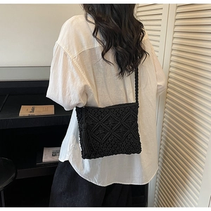 Detail of a black handwoven crossbody bag with diamond texture and large tassel accessory