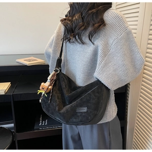 Détail du sac hobo croissant noir en cuir mat avec une jolie breloque ours de sac