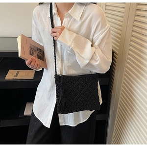 Detail of black macrame crossbody bag featuring diamond knit patterns and long tassels