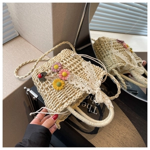 Detail of straw woven bucket bag with handmade crochet flowers and white lace trim