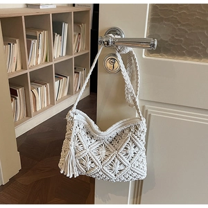 Detail of white handmade woven crossbody bag with fringe tassel on a silver handle