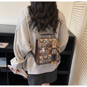 Detail view of the rhombus pattern fabric and brown leather trim on the backpack