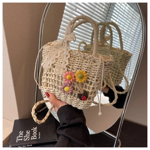 Detail of straw woven bucket bag featuring large lace bow and colorful fabric daisies