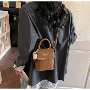 Brown frosted crossbody bag with gold rivet details shown carried by a model