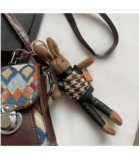 Gros plan d'un charm lapin en tricot marron avec gilet pied-de-poule sur un sac à main
