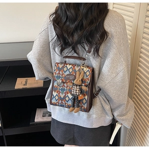 Detail of colorful geometric quilted backpack with leather trim and rabbit charm