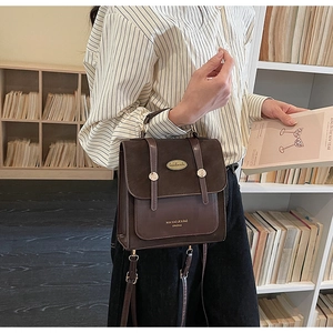 Detail van retro bruine suède handtas met metalen label in een literaire boekomgeving