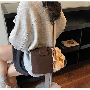 Gros plan d'un sac seau marron givré avec un pendentif peluche dans un café