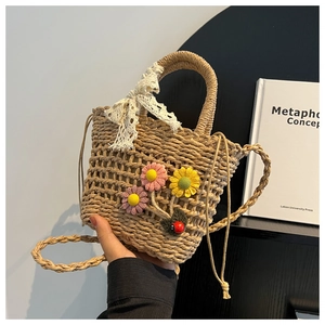 Detailed straw woven bucket bag featuring floral crochet accents and lace bow detail