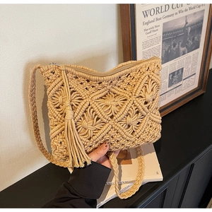 Close-up of handmade woven beige shoulder bag with cotton tassels and diamond texture