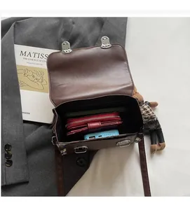 Vue détaillée de l'intérieur spacieux d'un sac à rabat matelassé marron avec accessoires