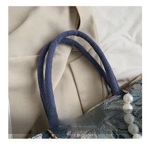 Detail showing woven rope handles and pearl chain on ethnic style jacquard tote bag