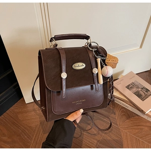 Detail van vintage donkerbruine kunstlederen tas met gespsluiting en baseball hanger