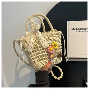 Close-up of woven straw handbag with lace bow, floral accents and drawstring closure