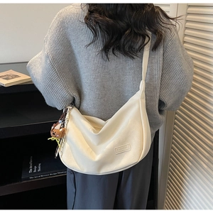 Sac bandoulière beige en demi-lune avec ourson en peluche porté par un mannequin