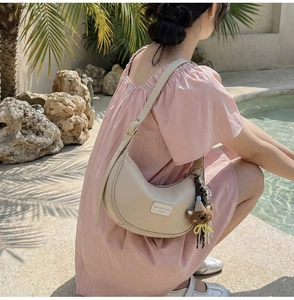 Close-up of beige hobo bag with adjustable strap and cute brown bear pendant