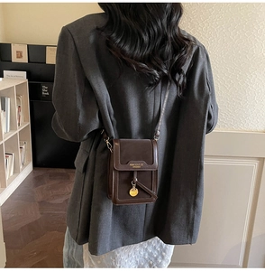 Detail of vintage coffee brown mini crossbody bag with gold pendant and tassel details
