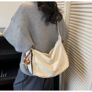 Détail d'un grand sac à main crème avec étiquette mode et accessoire de charme d'ours