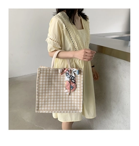 Close-up of stylish checkered tote bag with a decorative silk scarf on the side handle