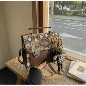 Détail du sac bandoulière en tissu à losanges avec finitions cuir et breloque lapin