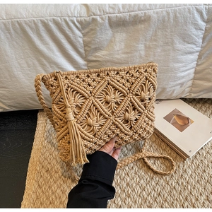Detailed close-up of handmade beige macrame bag with woven diamond pattern and tassel fringe