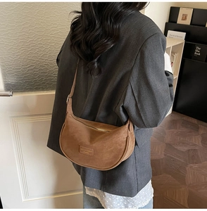 Detailed side view of a brown crescent shoulder bag with smooth zipper and leather strap