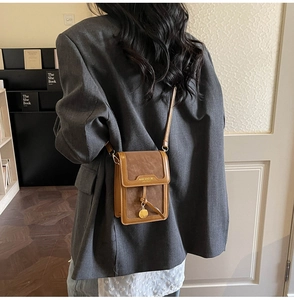 Detailed back view of a brown minimalist crossbody bag with metal disc charm and flap