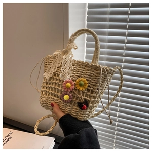 Detail of straw bucket bag with white lace bow and colorful floral ornaments