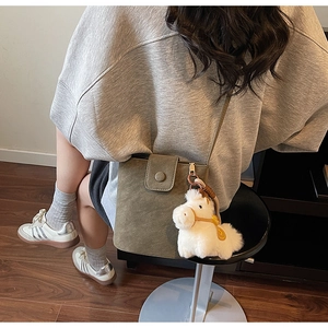 Détail d'un sac bandoulière vert olive avec son charme cheval en peluche blanc