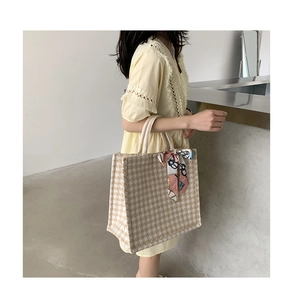 Detail of houndstooth tote bag with decorative silk scarf on handle and tweed texture