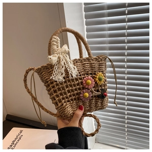 Detail of hand-woven straw bucket bag with crochet flowers and lace bow strap decoration
